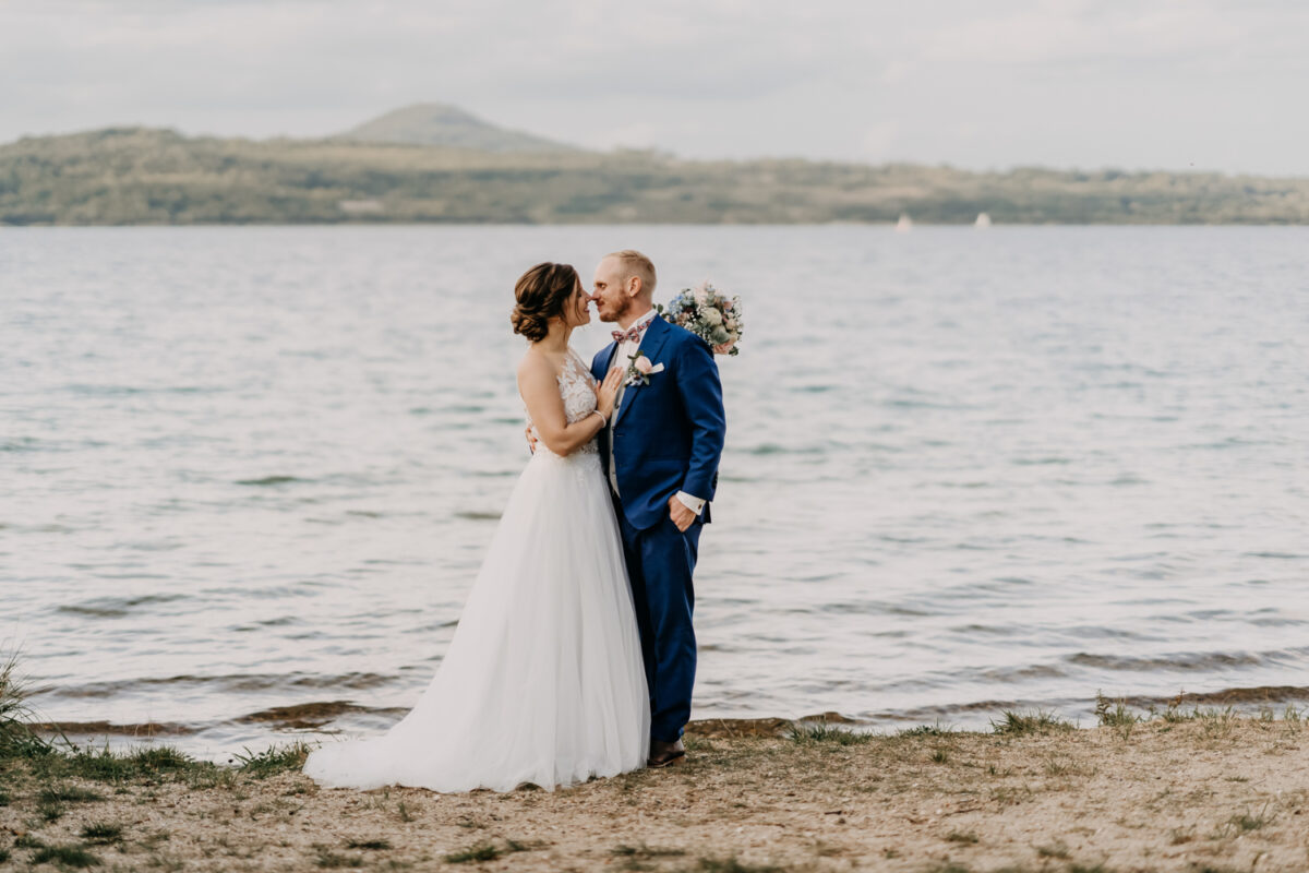 a man and woman in wedding attire kissing on a beach