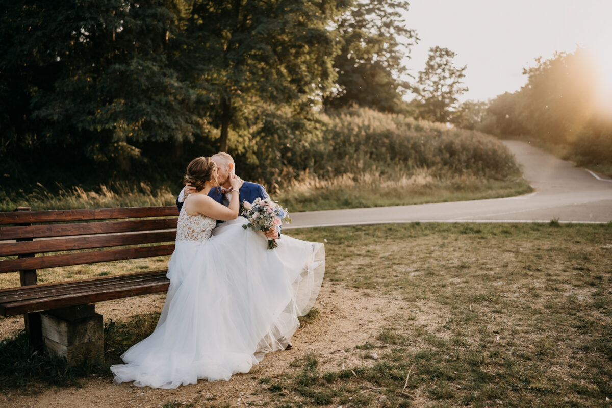 a man and woman sitting on a bench kissing